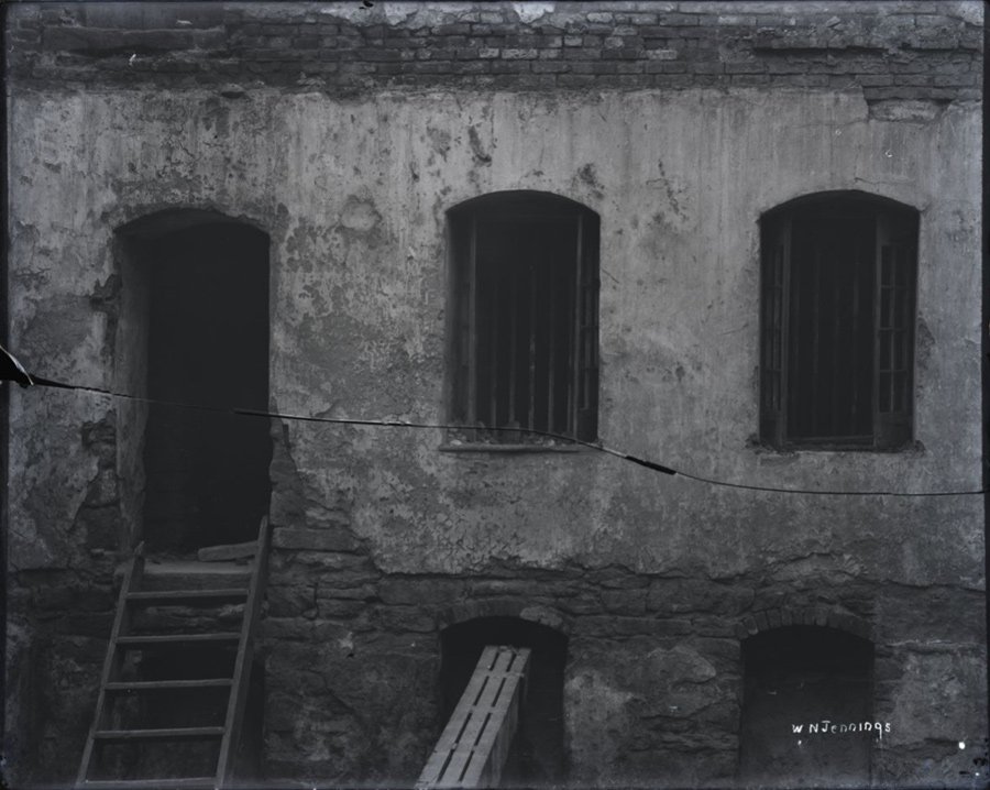 a black and white photo of a worn down building's doors and windows