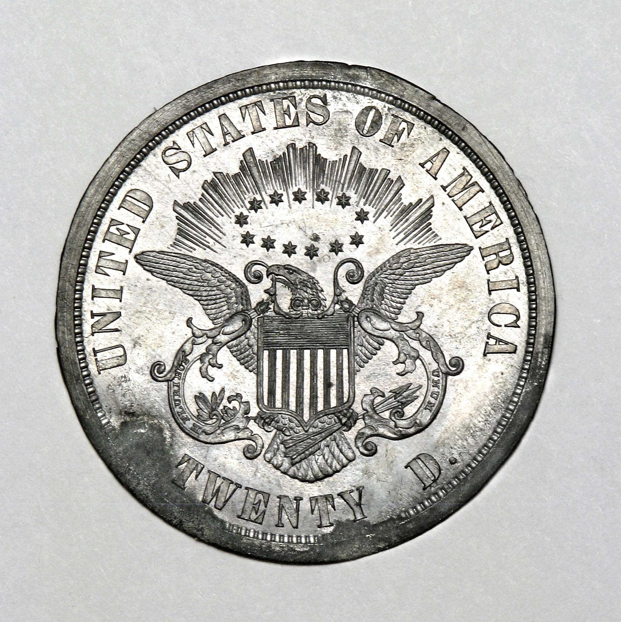 White metal disc impressed with an eagle holding an olive branch and arrows with rays and stars above its head.