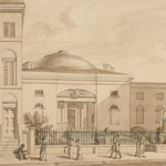 Domed building stands behind fence. Male and female pedestrians stroll along sidewalk in front of building