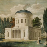 cCircular dome rises up from classical-style columned building situated in a grassy area. Smoke puff emerges from dome. Pedestrians promenade around building